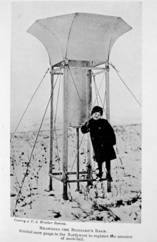 old time picture of a kid standing next to snow-guage