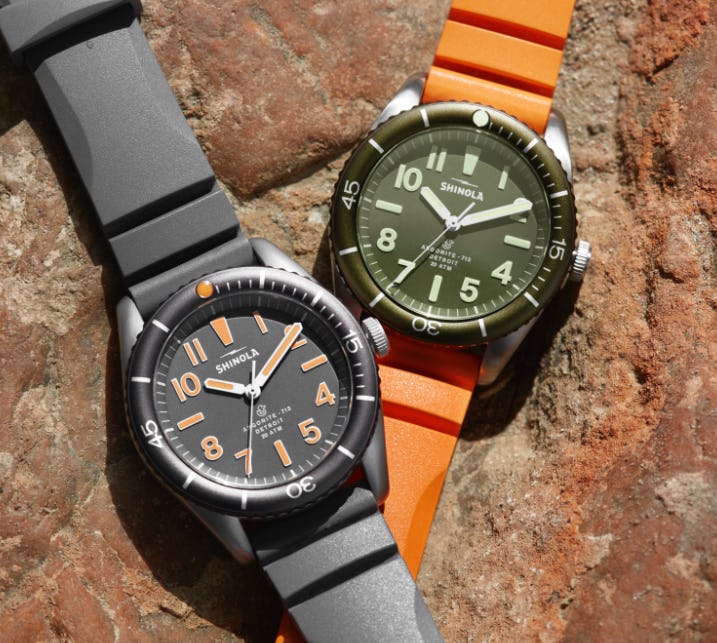 The Duck! watches, side-by-side, placed on a rock